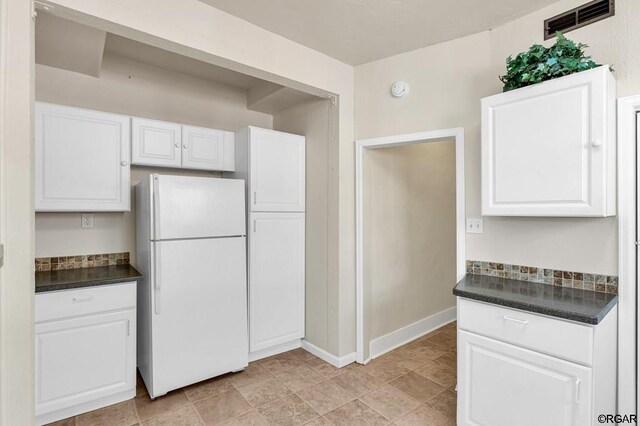 kitchen with white refrigerator and white cabinetry