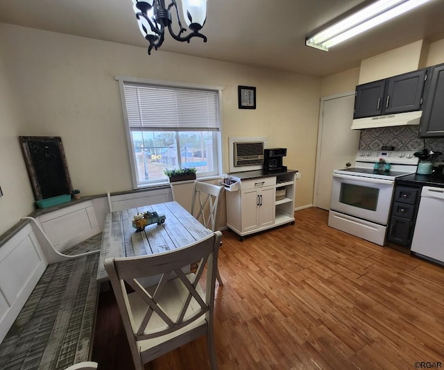 kitchen featuring hardwood / wood-style flooring, white appliances, a chandelier, and decorative backsplash