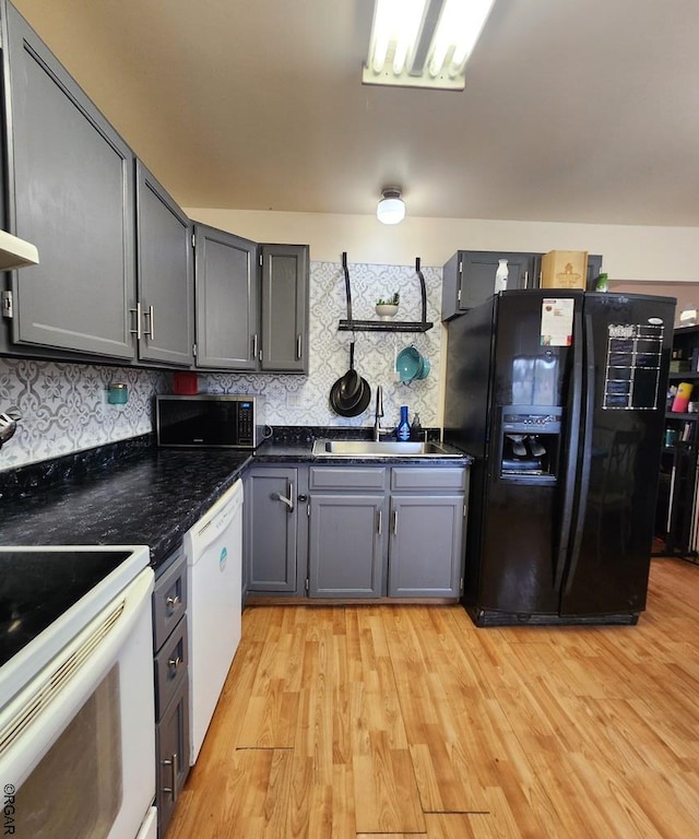 kitchen with sink, tasteful backsplash, light wood-type flooring, gray cabinets, and white appliances