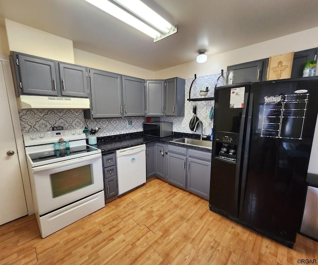 kitchen with sink, gray cabinetry, light wood-type flooring, white appliances, and backsplash