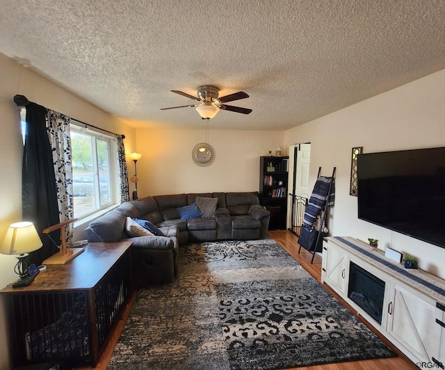 living room with ceiling fan, dark wood-type flooring, and a textured ceiling