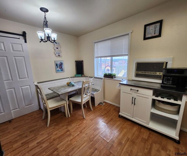 dining space featuring wood-type flooring, a barn door, a chandelier, and a wall mounted air conditioner