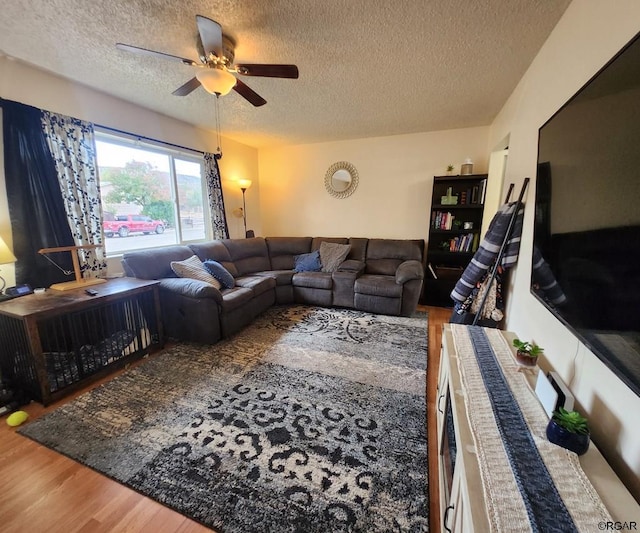 living room featuring wood-type flooring, ceiling fan, and a textured ceiling