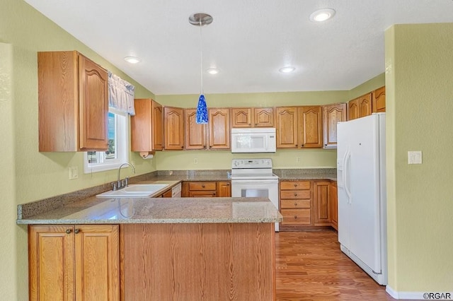 kitchen with sink, decorative light fixtures, light wood-type flooring, kitchen peninsula, and white appliances