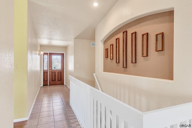 corridor with tile patterned flooring and a textured ceiling