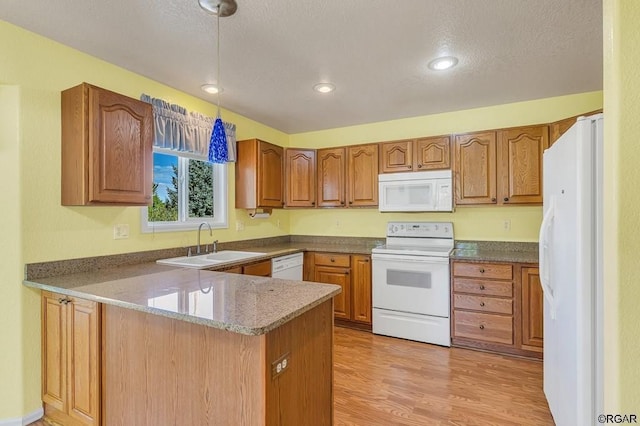 kitchen featuring sink, white appliances, kitchen peninsula, a textured ceiling, and light wood-type flooring