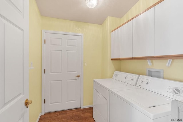 laundry area with hardwood / wood-style flooring, cabinets, and washer and clothes dryer