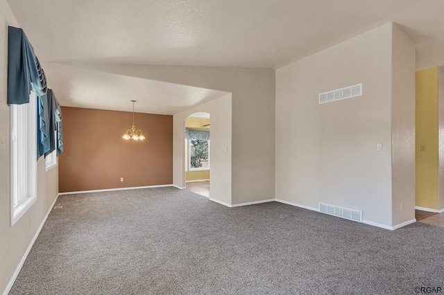 carpeted empty room with an inviting chandelier and lofted ceiling