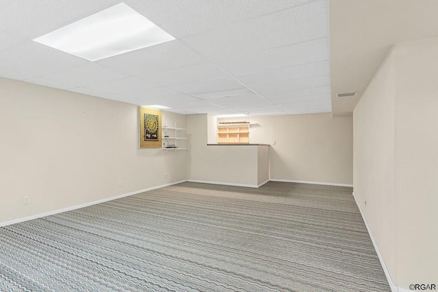 basement featuring a drop ceiling and carpet