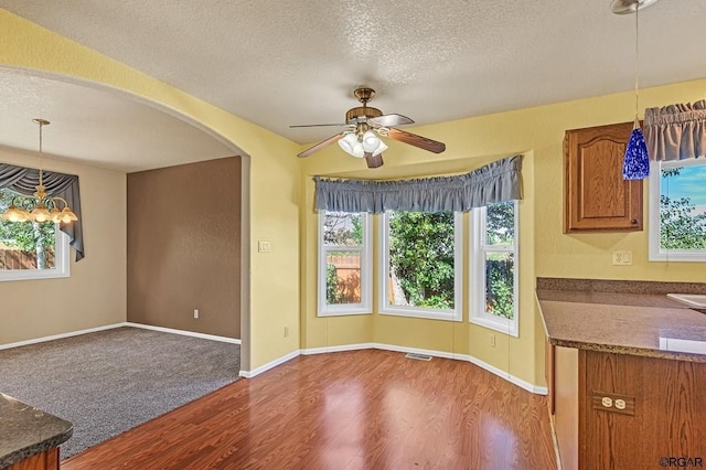 unfurnished dining area featuring dark hardwood / wood-style flooring, ceiling fan, and a textured ceiling