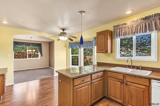 kitchen featuring white dishwasher, sink, kitchen peninsula, and a textured ceiling