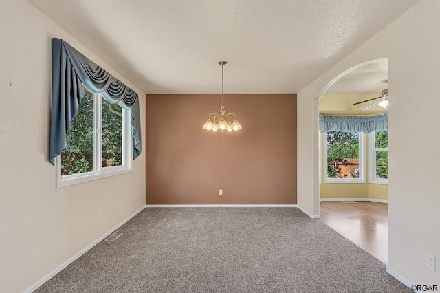 carpeted spare room with ceiling fan with notable chandelier and a textured ceiling