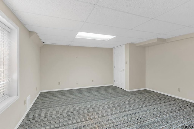 carpeted spare room featuring a drop ceiling