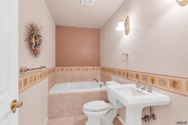 bathroom with sink, toilet, tile patterned flooring, and tiled tub