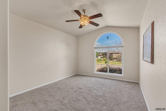 carpeted empty room with ceiling fan, vaulted ceiling, and a textured ceiling