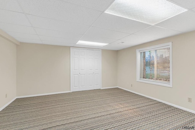 unfurnished room with a paneled ceiling and carpet