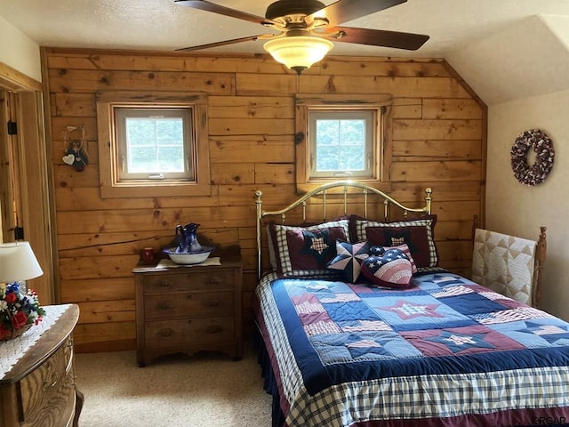 carpeted bedroom featuring vaulted ceiling, ceiling fan, and wood walls