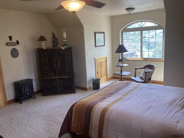 carpeted bedroom with vaulted ceiling, a wood stove, and ceiling fan