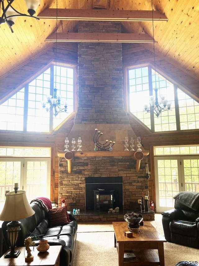 carpeted living room featuring beam ceiling, a stone fireplace, high vaulted ceiling, and wooden ceiling