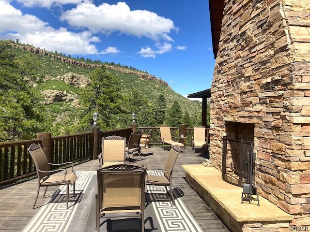 wooden deck with a mountain view and an outdoor stone fireplace