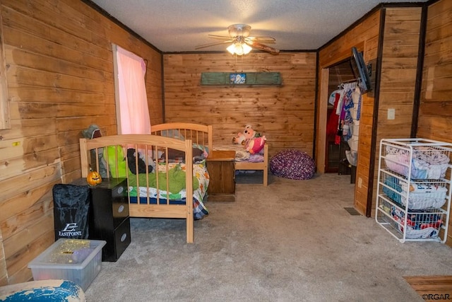 carpeted bedroom with ceiling fan, wooden walls, and a textured ceiling