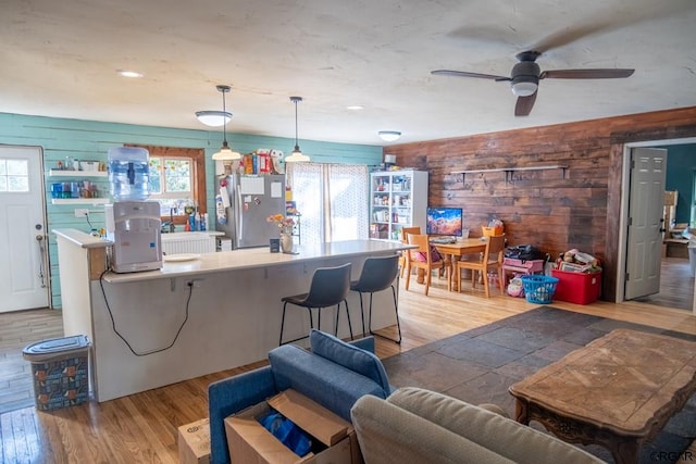 interior space with ceiling fan, hardwood / wood-style floors, and wooden walls