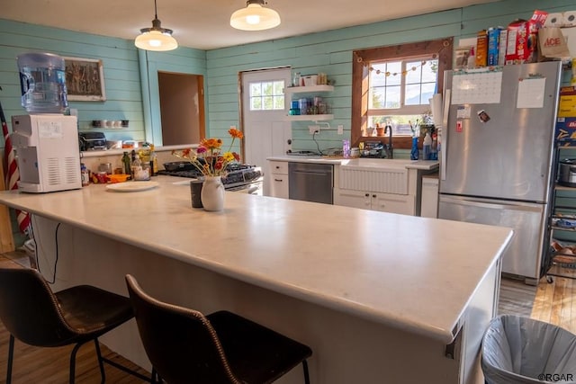 kitchen with sink, appliances with stainless steel finishes, hanging light fixtures, a kitchen breakfast bar, and white cabinets