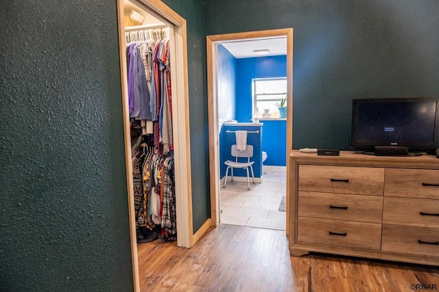 bedroom with a walk in closet, a closet, and light wood-type flooring