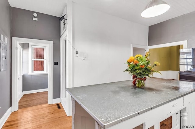 interior space with light wood-style floors, a wealth of natural light, light countertops, and baseboards