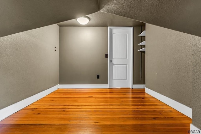 bonus room featuring wood finished floors and a textured wall