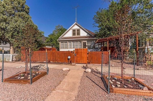 exterior space featuring a fenced front yard, a gate, and a vegetable garden