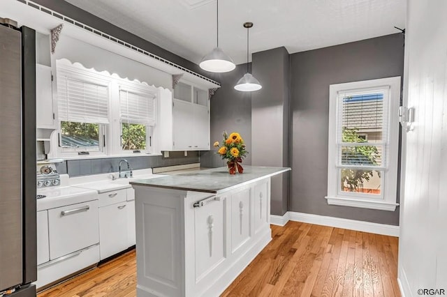 kitchen with range, a center island, white cabinetry, and pendant lighting