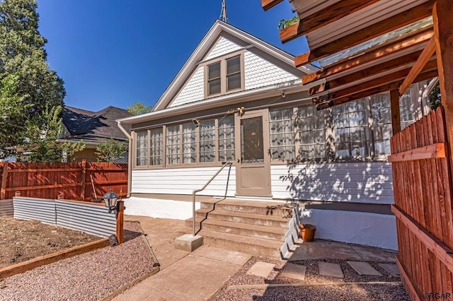 view of front of home with a sunroom and fence