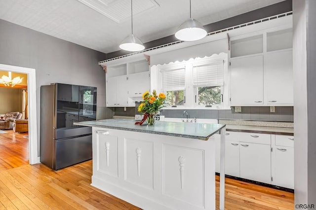 kitchen with white cabinets, hanging light fixtures, and refrigerator with glass door