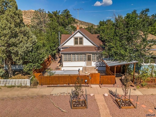 rear view of property with a mountain view, a fenced front yard, and a gate