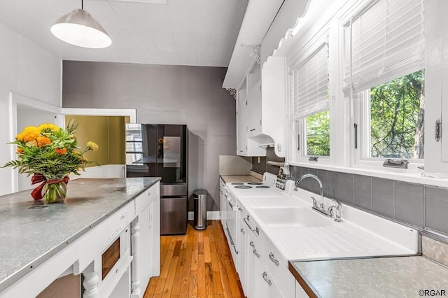 kitchen with white range with electric cooktop, decorative light fixtures, light countertops, white cabinetry, and a sink