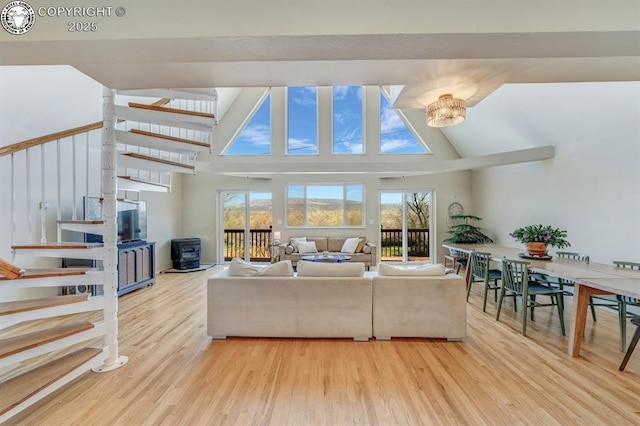living area with high vaulted ceiling, stairway, and wood finished floors