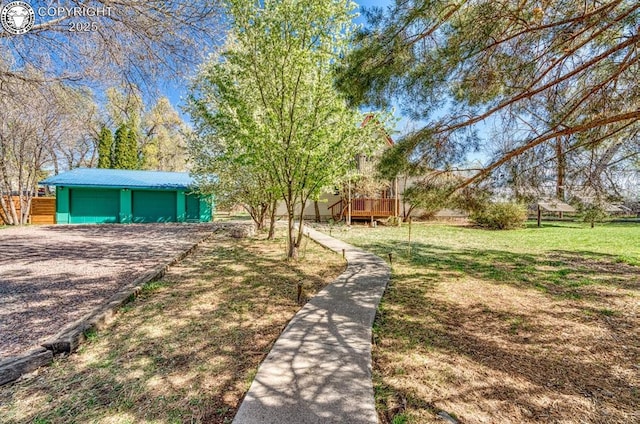 view of front of property with an outbuilding, a detached garage, a deck, and a front lawn