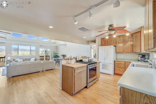 kitchen with light countertops, a sink, stainless steel range with gas cooktop, and freestanding refrigerator