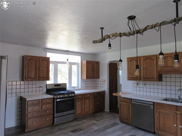 855 Ernest Ave, Westcliffe, CO 81252 - kitchen featuring stainless steel appliances, decorative backsplash, light wood finished floors, and brown cabinets