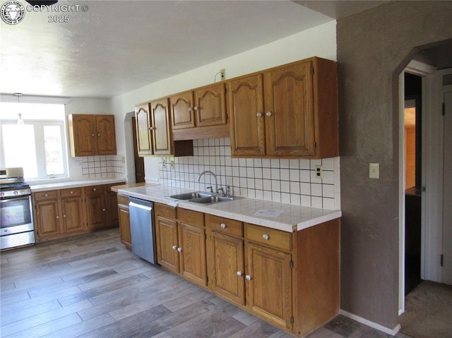 855 Ernest Ave, Westcliffe, CO 81252 - kitchen featuring appliances with stainless steel finishes, brown cabinets, decorative backsplash, arched walkways, and light wood-style floors