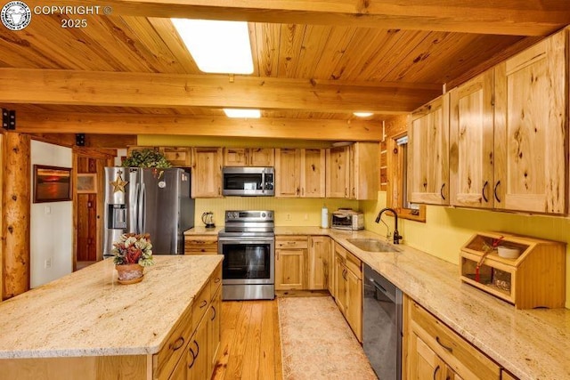 kitchen with sink, stainless steel appliances, a center island, and light stone countertops