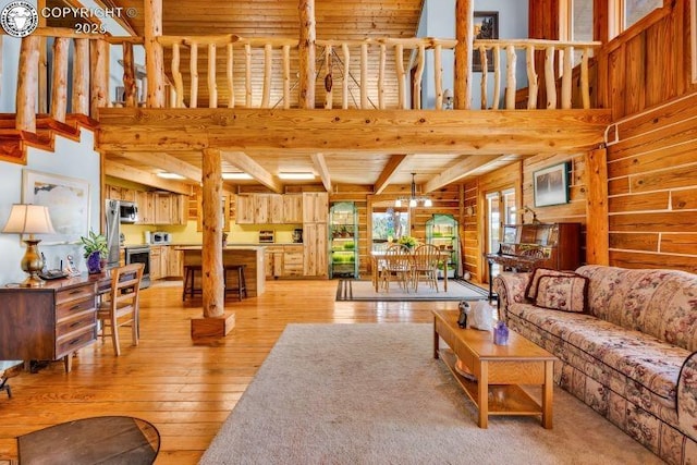 living room with beamed ceiling, rustic walls, a high ceiling, wooden ceiling, and light hardwood / wood-style flooring