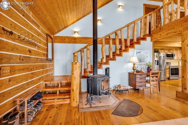 stairway with wood-type flooring, a wood stove, wooden ceiling, and high vaulted ceiling