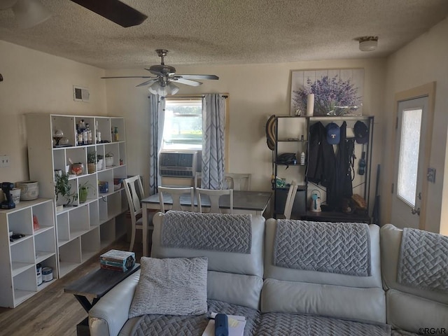 living room with ceiling fan, hardwood / wood-style floors, a textured ceiling, and cooling unit