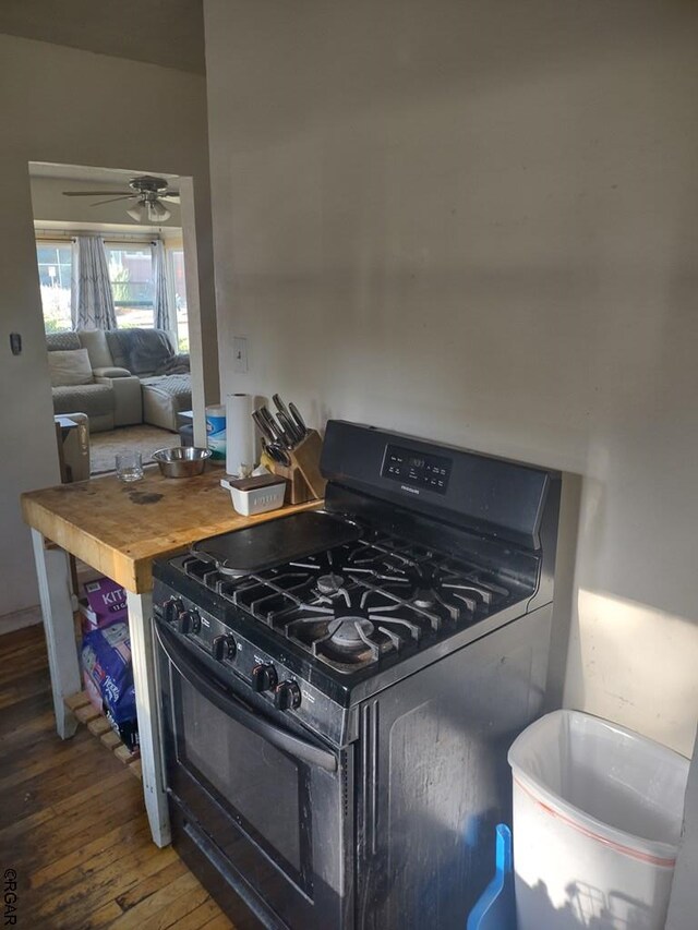 kitchen featuring dark wood-type flooring, ceiling fan, butcher block counters, and black gas range