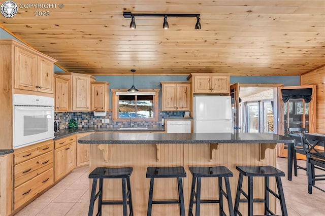 kitchen with a sink, white appliances, light tile patterned flooring, and light brown cabinets