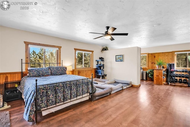 bedroom featuring a wainscoted wall, a textured ceiling, and wood finished floors