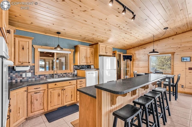 kitchen with tasteful backsplash, dark countertops, light tile patterned floors, white appliances, and a sink