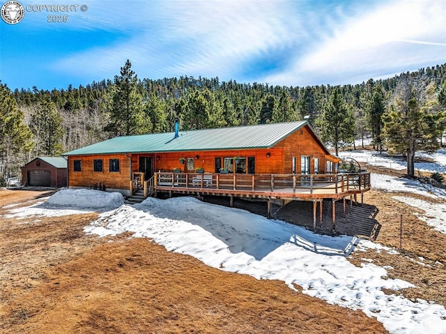 chalet / cabin featuring a deck, a detached garage, and a wooded view